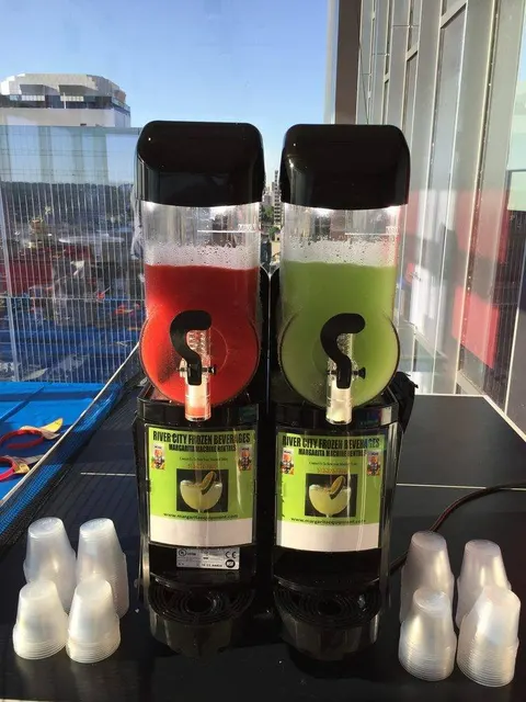 Strawberry and lime machine with cups at a rooftop pool party